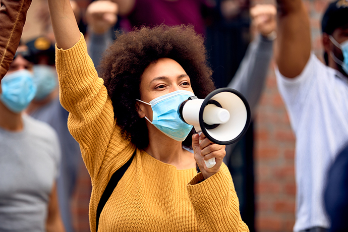 Black woman wearing mask and speaking into megaphone